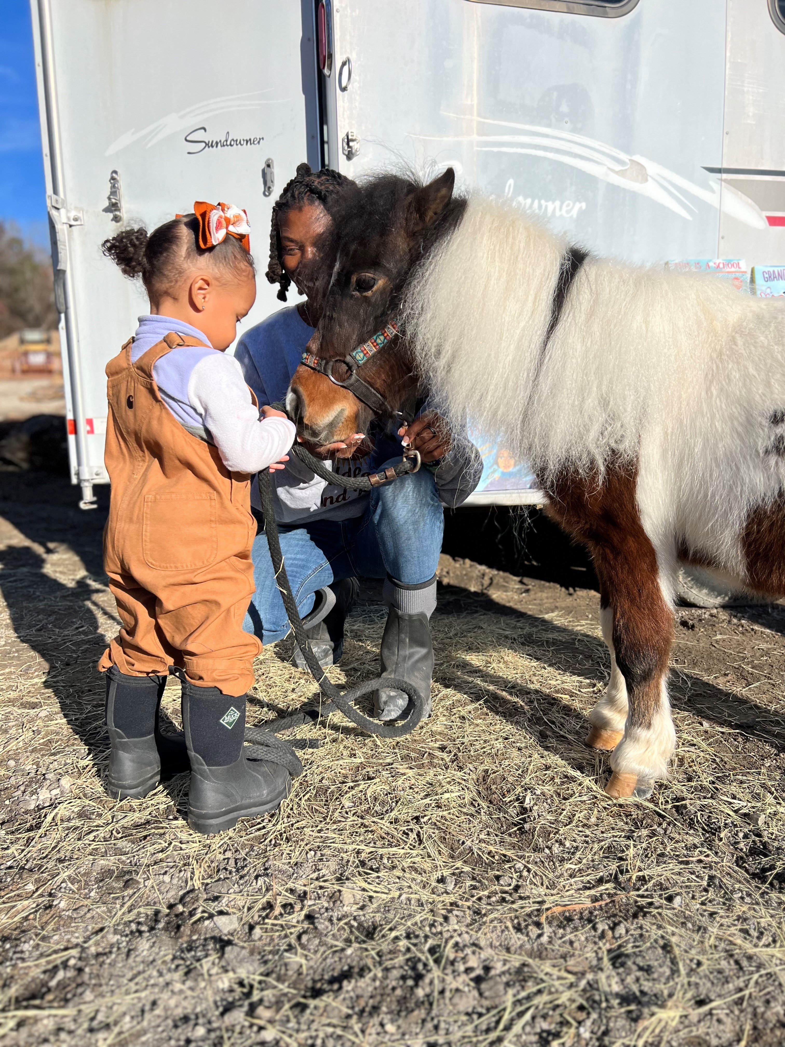 Caitlin and a little child with a brown and white pony.