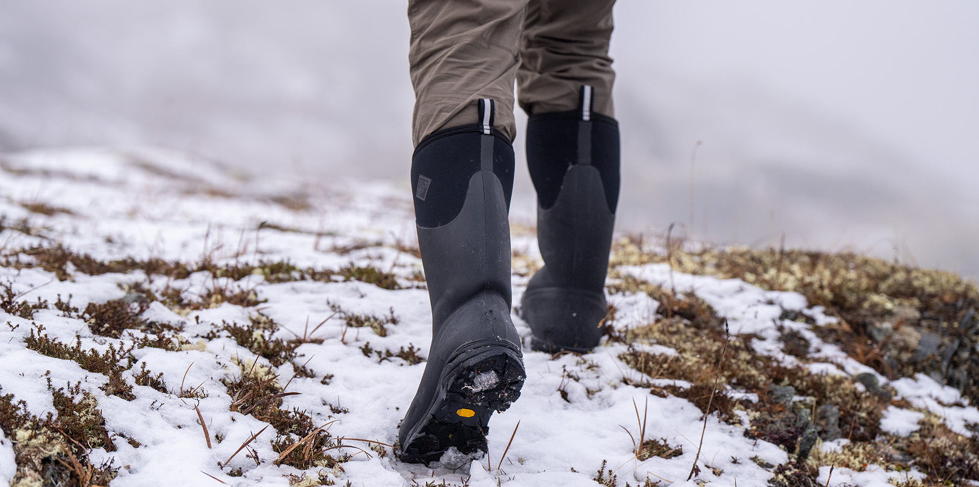 person wearing muck Sport ankle boots while picking up fire wood