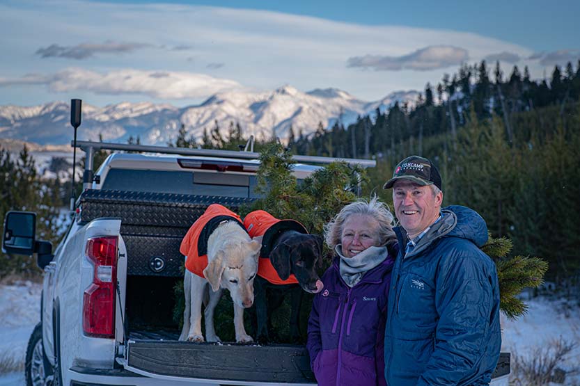 Jody any his wife posing with their dogs in front of a beautiful mountain scape.