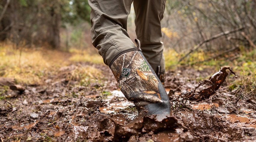 Man walking through muddy woods wearing Muck Men's Hunting Boots