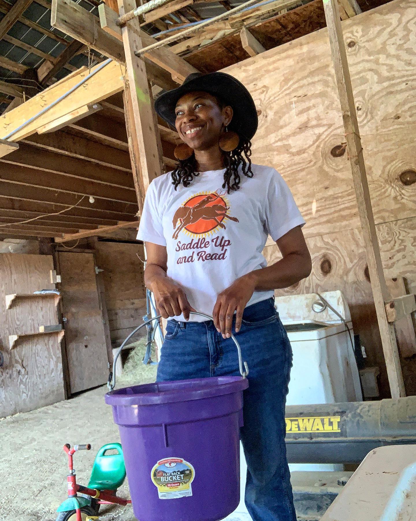 Caitlin, holding a purple bucket, with a wide smile.