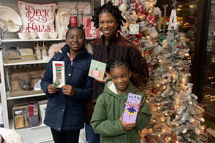 Caitlyn with her children in a Christmas store, holding up books