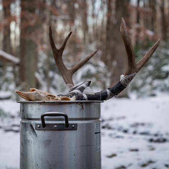 An antler sitting atop a metal pot on the snow.