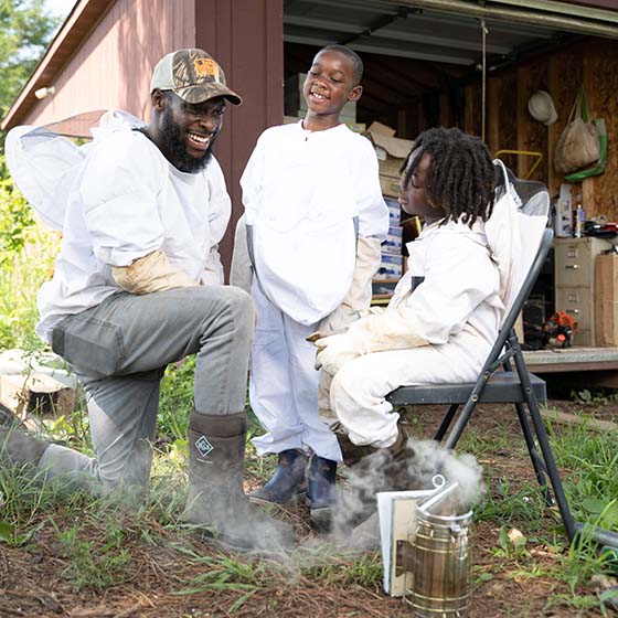 Kamal Bell, owner of Sankofa Farm, sitting and talking with kids at the farm.