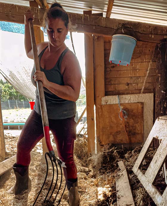 Elizabeth cleaning out the barn with a pitchfork