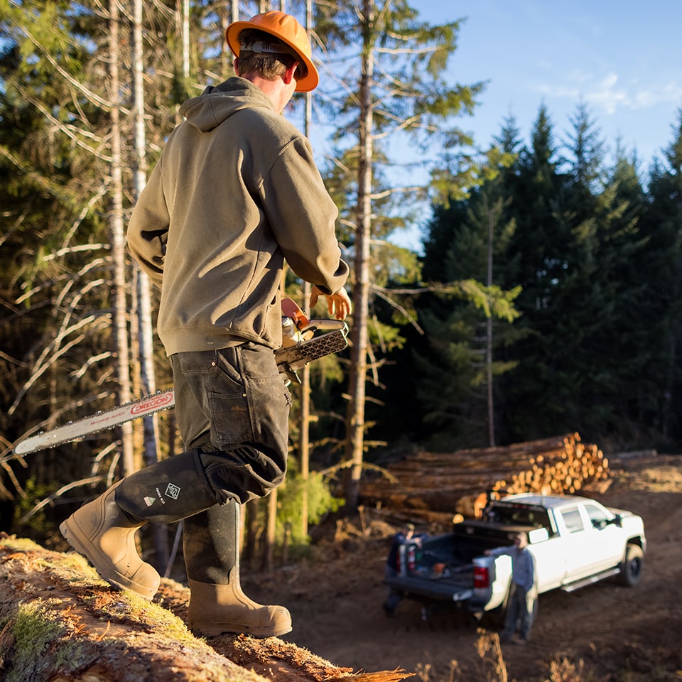 Worker with chainsaw in the forest wearing Muck Chore Classic Tall Steel Toe