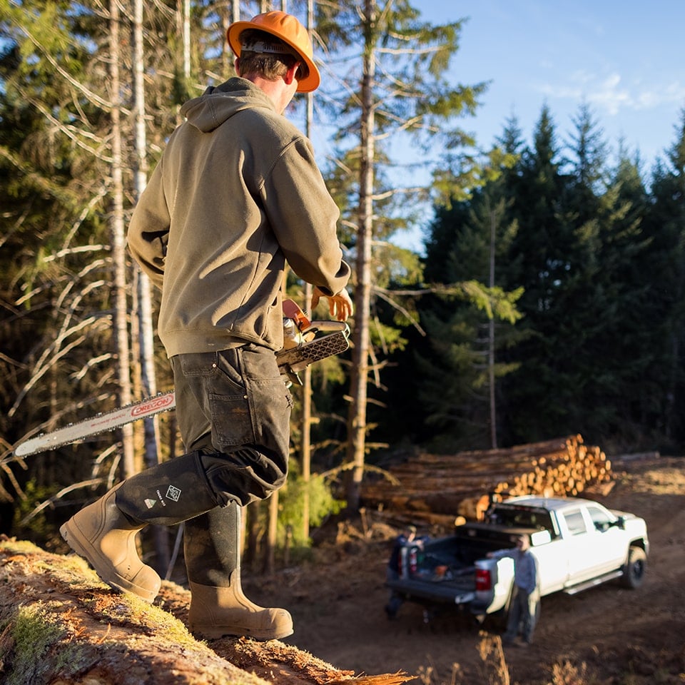 Worker with chainsaw in the forest wearing Muck Chore Classic Tall Steel Toe